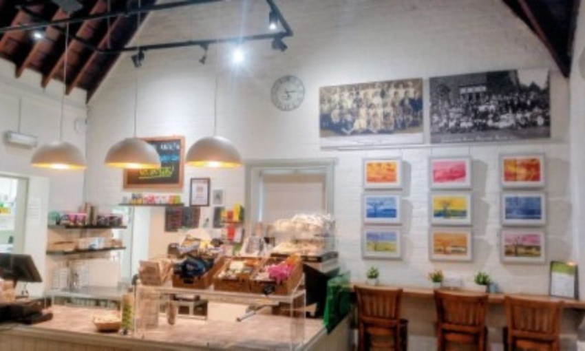 Image shows a small community cafe with a wall displaying 9 pieces of artwork from Swanmore College